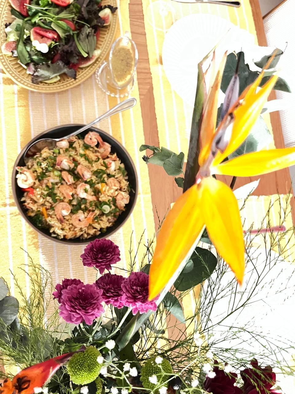 Arroz de camarão servido em mesa posta com arranjo floral