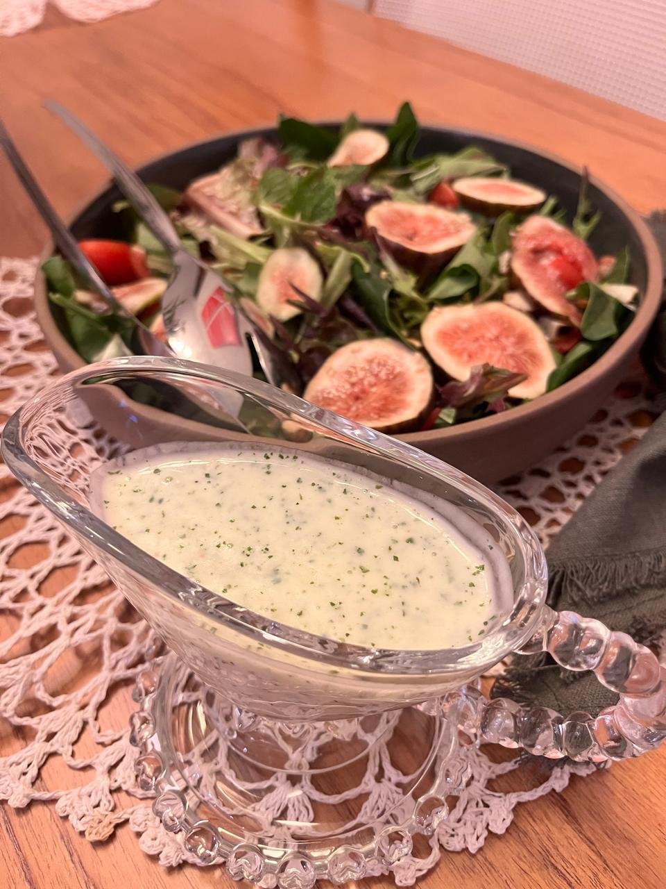 Molho de iogurte servido em molheira de vidro ao lado da salada