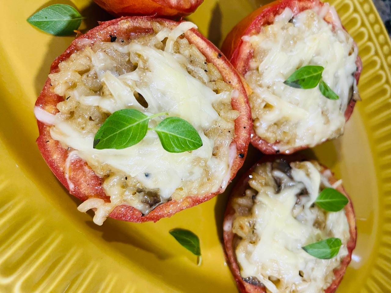 Tomates recheados assados servidos em prato amarelo