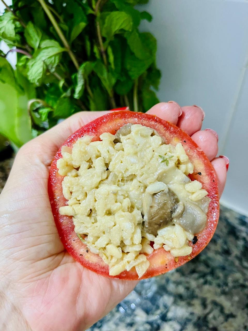 Tomate recheado com risoto de cogumelos na mão antes da finalização